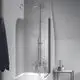 Duschsystem von Ideal Standard mit Oberteil, Handbrause und Schlauch. Montiert an einer Wand, neben einer Badewanne und einem kleinen Tisch mit Pflegeprodukten.